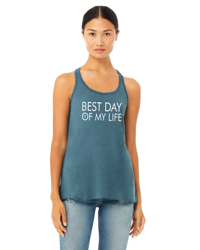 medium skinned person wearing a blue tank top with best day of my life written across in white and a cross in the O