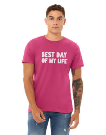 young light-brown skinned man with a half sleeve tattoo wearing a pink crewneck t-shirt with best day of my life written across in white block lettering