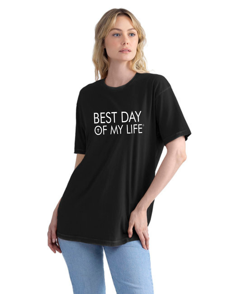 light skinned person with blonde hair wearing a black crewneck t-shirt with best day of my life written in white with a cross in the O