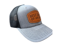 Gray and black trucker cap with brown leather patch on a white background