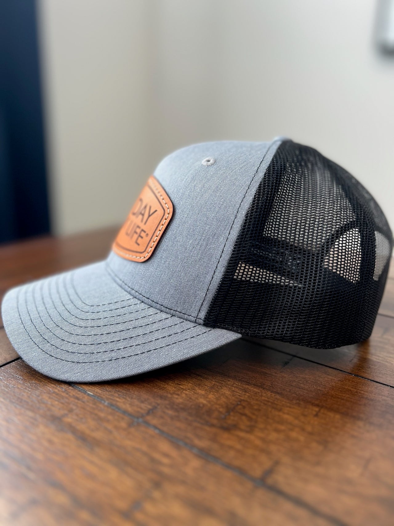 Gray and black cap with a leather patch on a wooden surface